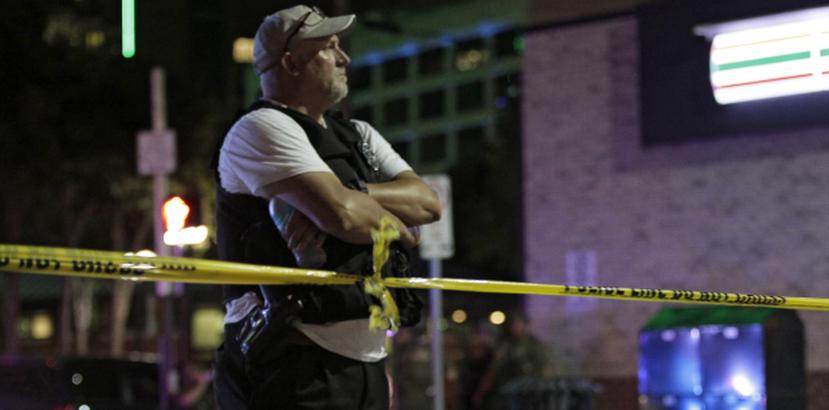 Un agente de la policía de Dallas observa tras el cordón policial en al escenario del tiroteo. (EFE / Ralph Lauer)