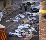 Varios médicos, junto a los cadáveres cubiertos de las víctimas de un incendio en un edificio del centro de Johannesburgo, el 31 de agosto de 2023.