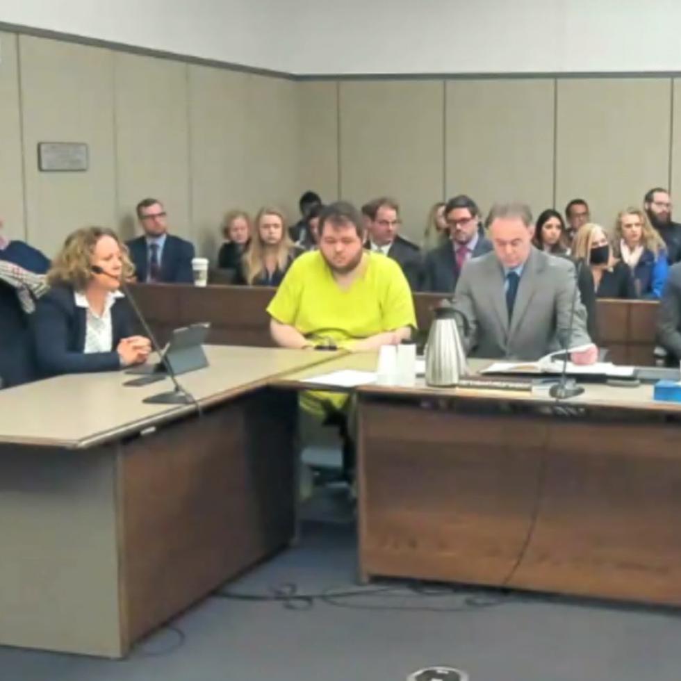 En esta imagen tomada de un video de la Corte de Distrito del Condado El Paso, Anderson Lee Aldrich, de 22 años, en el centro, permanece sentado durante una audiencia en Colorado Springs.