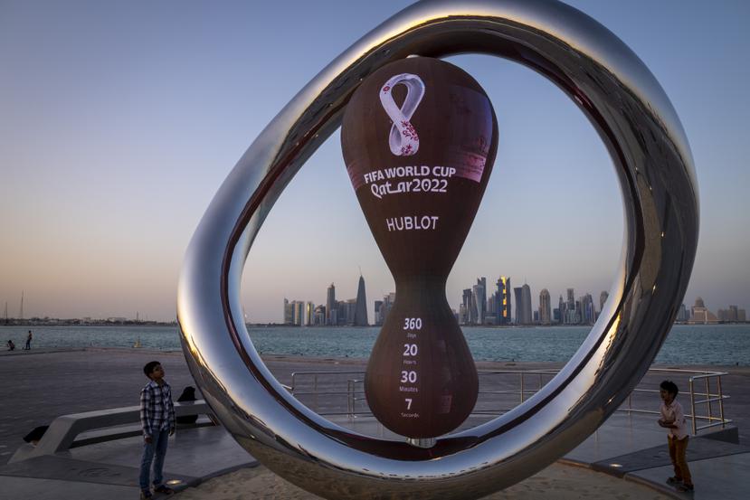 Un par de niños observa el reloj que marca la cuenta regresiva hacia el Mundial de Catar en Doha.