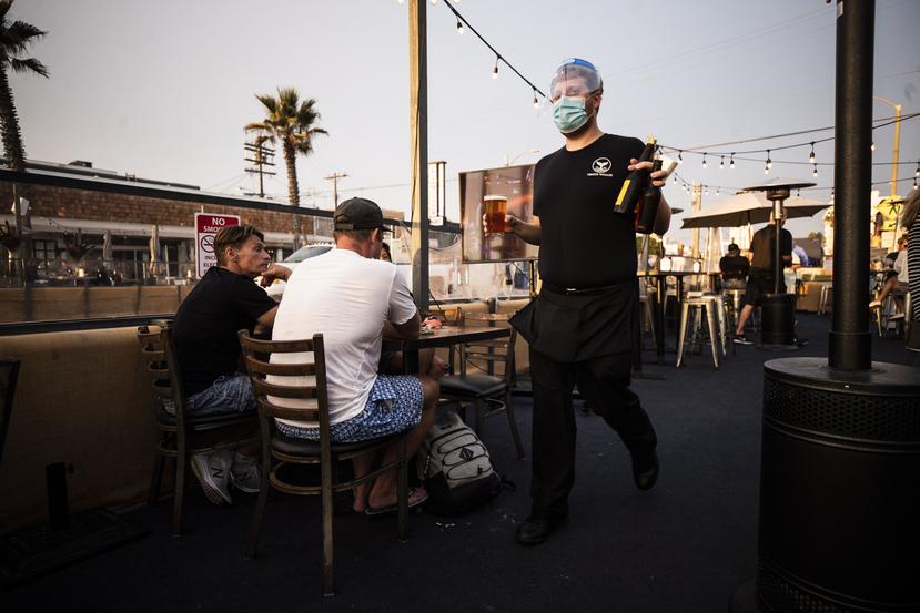 Un mesero atiende comensales en un restaurante en Venice Beach, California.