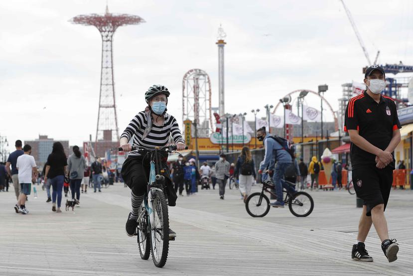 A woman rides her bicycle on the boardwalk at Coney Island during the current coronavirus outbreak. (AP)