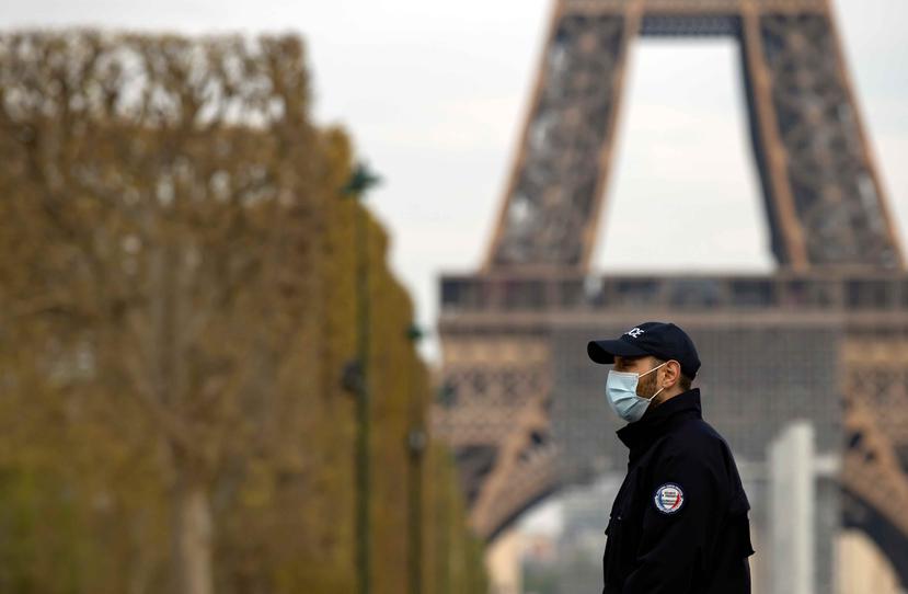 Hombre posa frente a la Torre Eiffel en París usando una mascarilla. (AP)