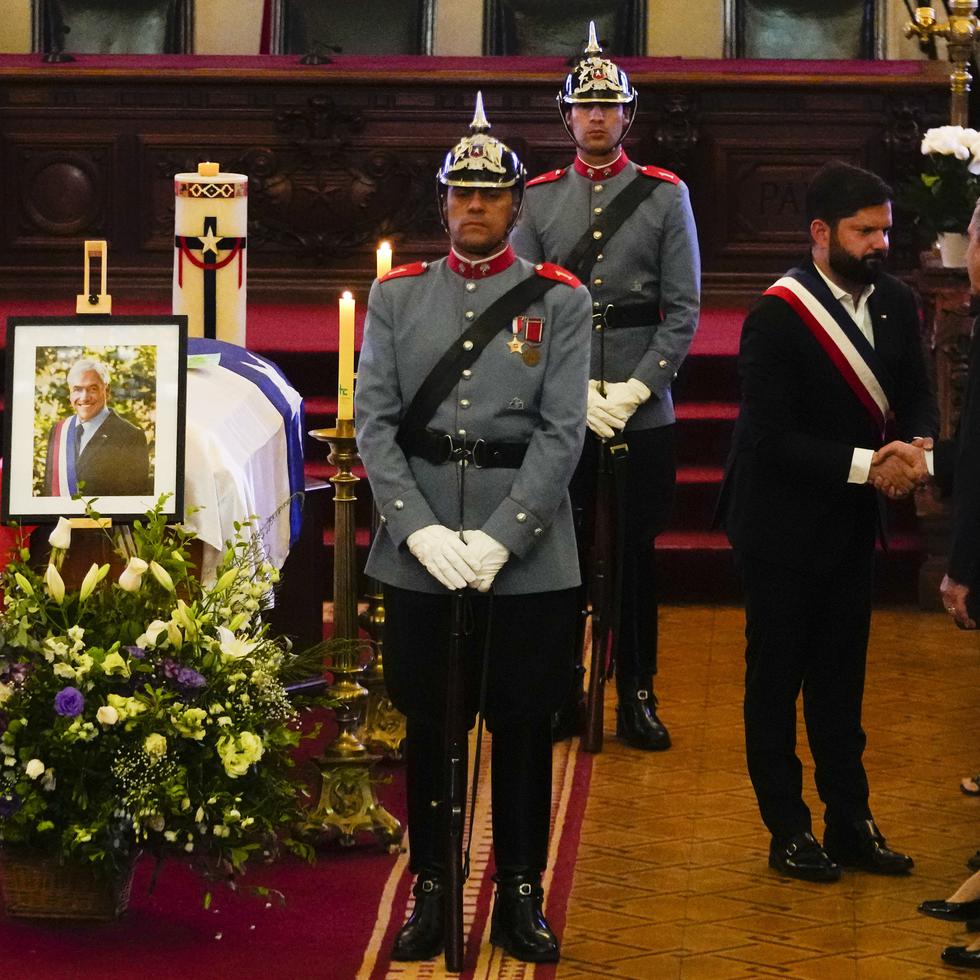 El presidente de Chile, Gabriel Boric, en el centro, le da la mano al exmandatario chileno Eduardo Frei junto al ataúd del fallecido presidente chileno Sebastián Piñera durante su velorio.