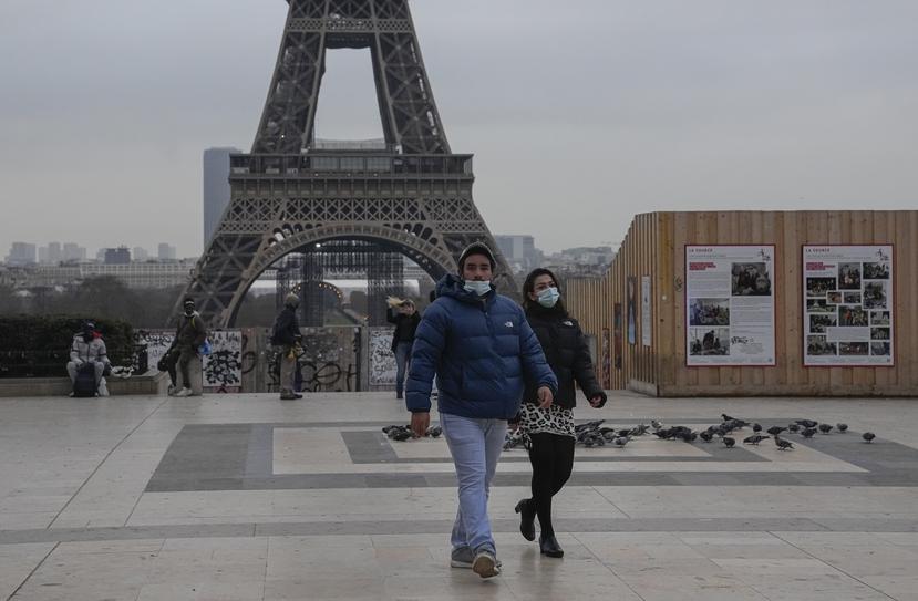 Dos personas, con mascarilla por la pandemia del coronavirus, cruzan la Plaza del Trocadero, en París.