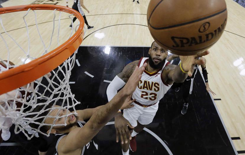 El alero de los Cavaliers de Cleveland, LeBron James, dispara contra la defensa de los Spurs de San Antonio, Kawhi Leonard, durante la primera mitad del juego. (AP)
