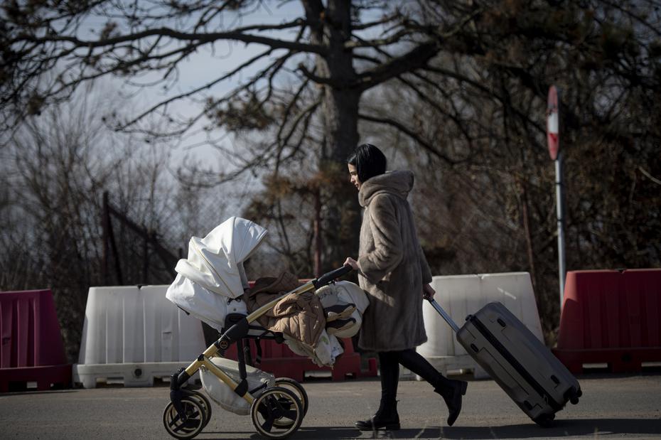 A woman with her belongings and her baby leaves Ukraine on her way to Romania.