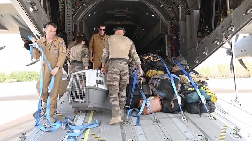 En esta imagen de video proporcionada por las fuerzas armadas francesas, personal militar carga en un avión las pertenencias de personas evacuadas, el domingo 23 de abril de 2023, en el aeropuerto de Jartum, Sudán.