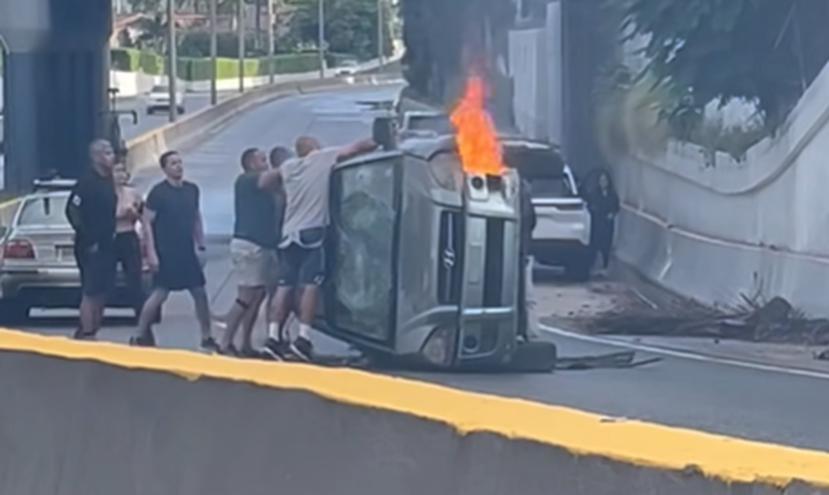 Momento en el que rescatan con vida a una mujer luego que su auto se volcara y se incendiara en San Juan. 