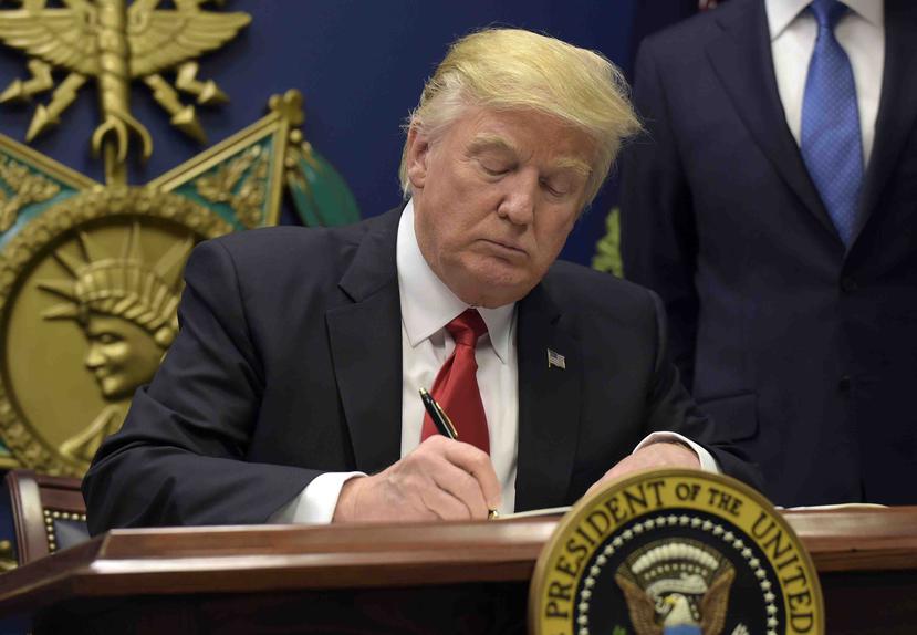 El presidente Donald Trump firma un decreto que frena la llegada de refugiados. (AP)