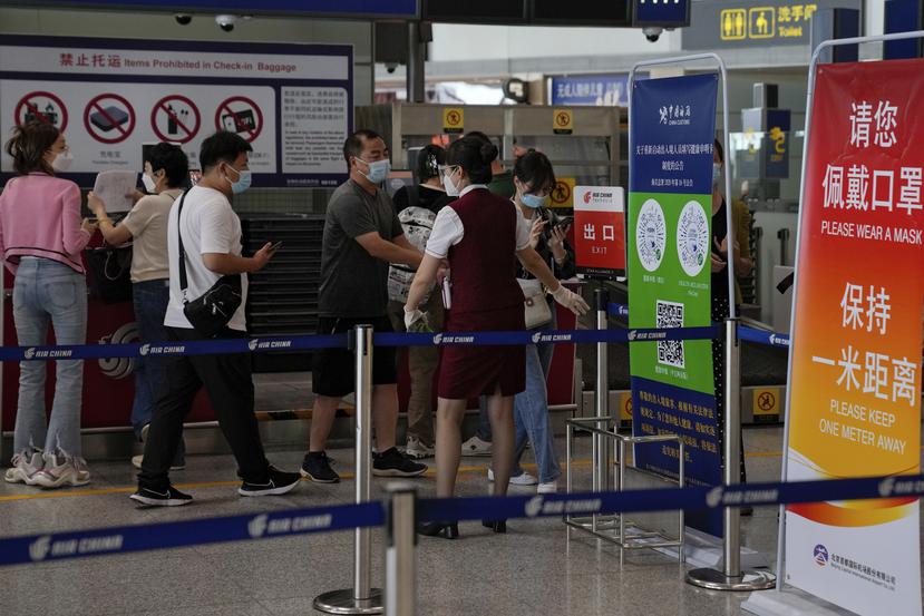 Una trabajadora aérea pide a los viajeros que declaren su información de salud tras facturar en el mostrador de vuelos internacionales en el aeropuerto internacional de Pekín.