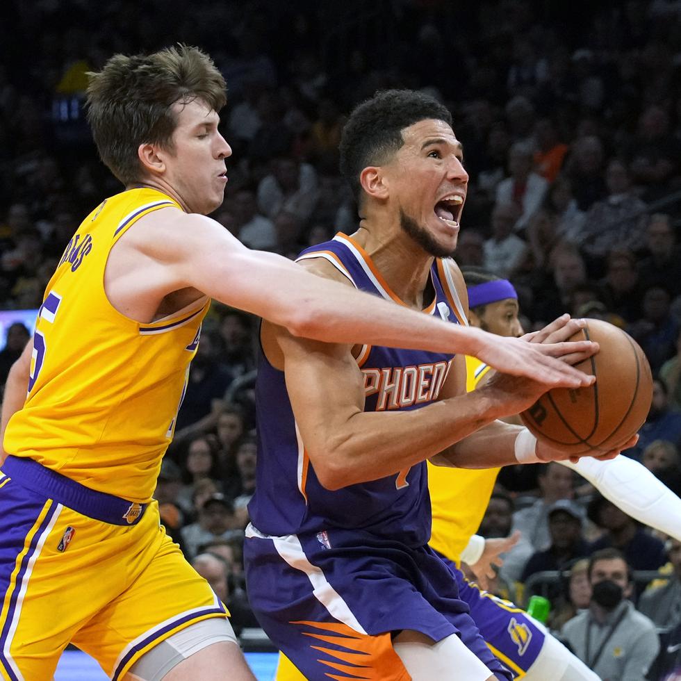 El escolta de los Lakers de Los Ángeles Austin Reaves, a la izquierda, comete una falta sobre el escolta de los Suns de Phoenix Devin Booker durante la segunda mitad de un partido de baloncesto de la NBA el martes 5 de abril de 2022, en Phoenix.