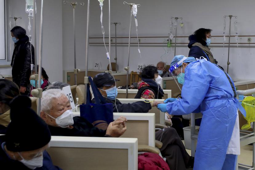 En esta foto publicada por la Agencia de Noticias Xinhua, un trabajador médico ayuda a un paciente con el goteo intravenoso en una institución de salud comunitaria en Shanghái, China.