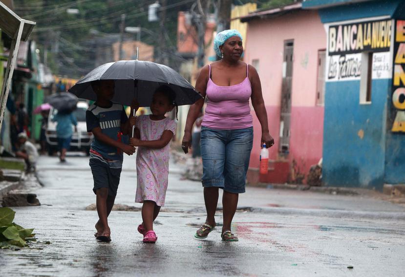 Una mujer y dos niños caminan hoy en el barrio La Ciénaga, en Santo Domingo. (EFE)
