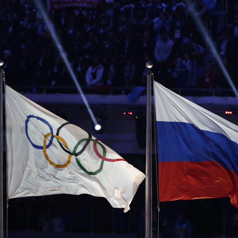 La bandera de Rusia (derecha) ondea junto a la de los Juegos Olímpicos durante la ceremonia de clausura de los Juegos de Invierno, en Sochi 2014.