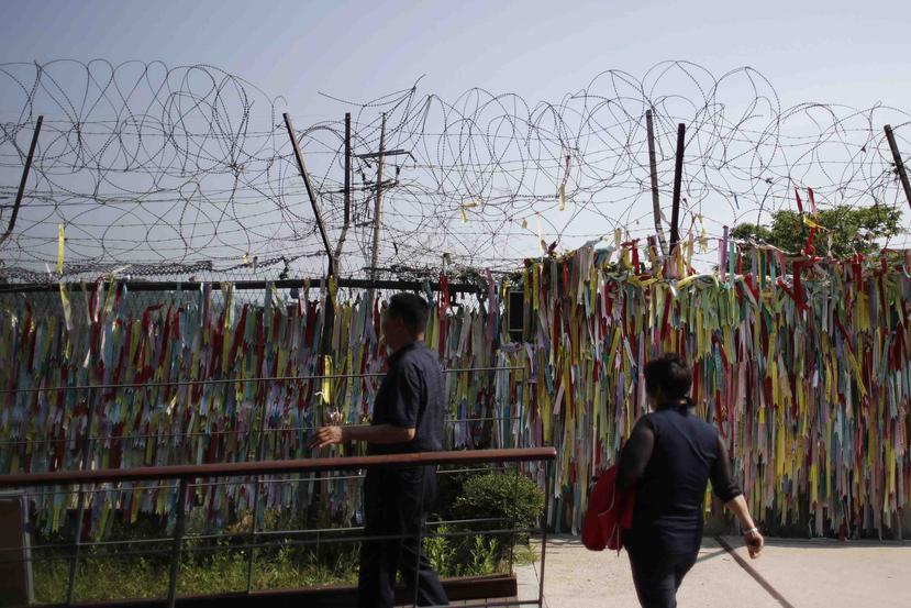 Personas miran cerca de alambre en la frontera entre Corea del Sur y Norte decorada con cintas escritas con mensajes que desean la reunificación de las dos Coreas. (AP)