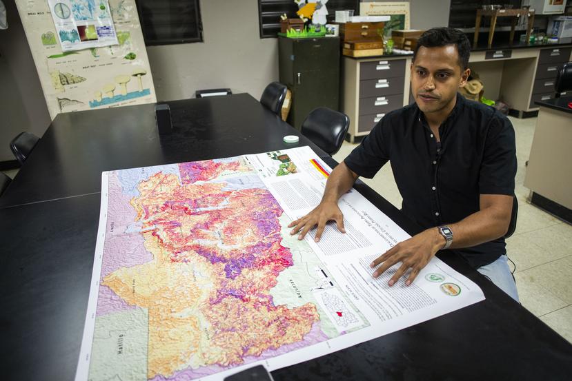 Luis Alexis Rodríguez Cruz, investigador de la UPR en Utuado, frente al mapa que muestra las zonas de vulnerabilidad a deslizamientos.