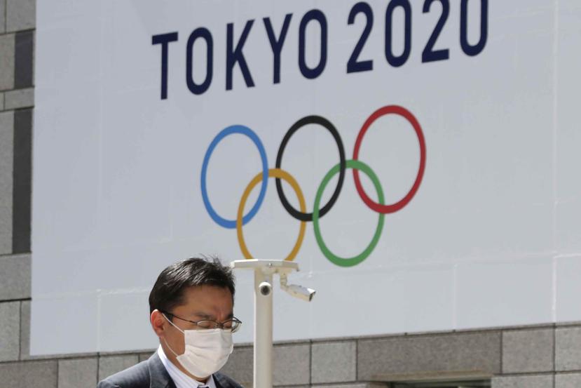 Un hombre camina frente a un arte de los Juegos Olímpicos hoy, miércoles, en el área metropolitana de Tokio. (AP)