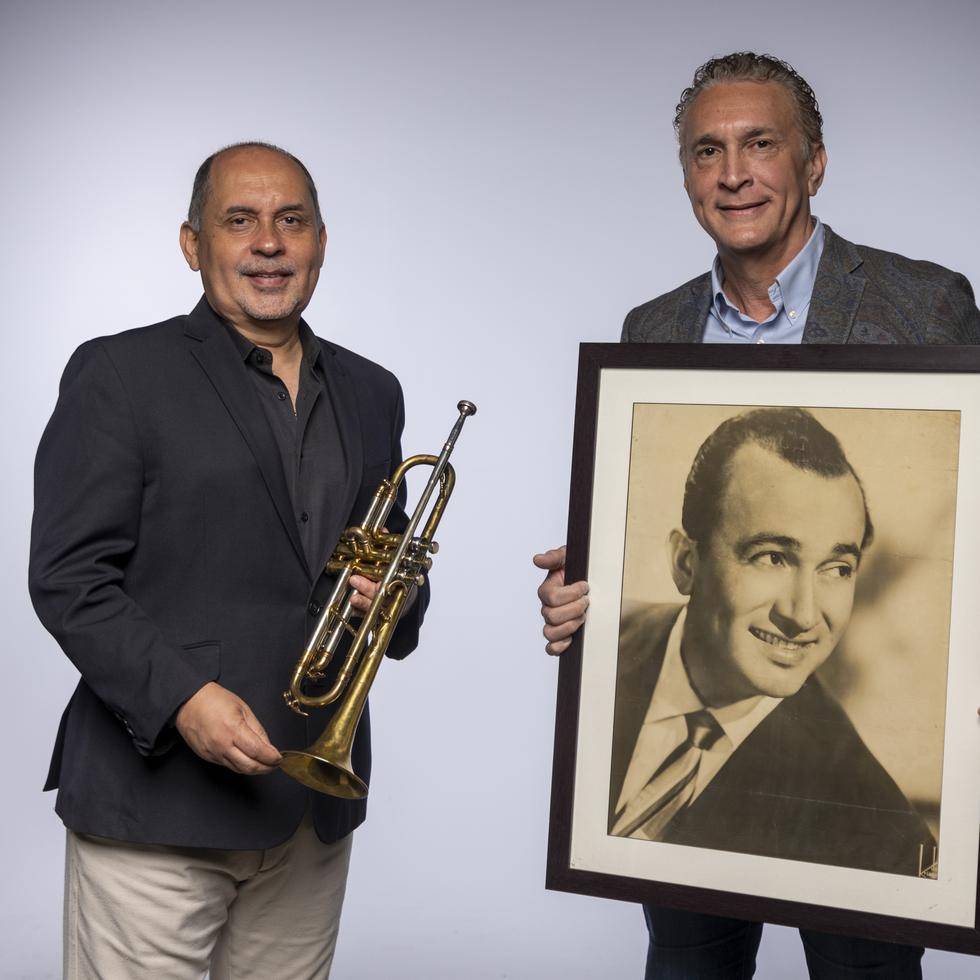 El destacado músico Humberto Ramírez sostiene la trompeta original de César Concepción, la cual aún se puede tocar; mientras César Concepción, hijo, muestra un retrato de su talentoso progenitor.