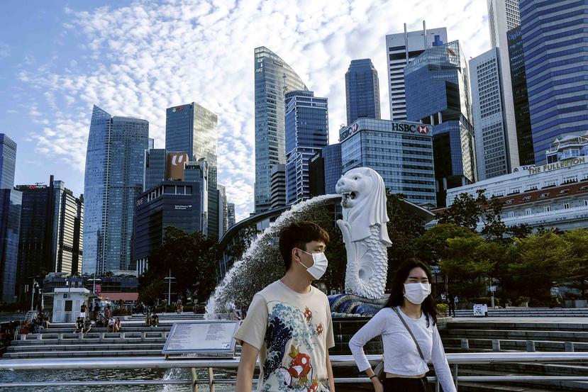 Una pareja con mascarillas pasea junto a la estatua del Merlion en Singapur. (AP)