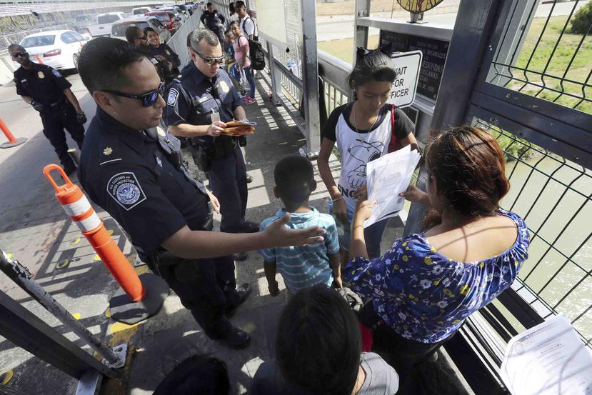 Un agente de la Oficina de Aduanas y Protección Fronteriza verifica los documentos de migrantes antes de que sean llevados a solicitar asilo en Estados Unidos. (AP Foto/Marco Ugarte)