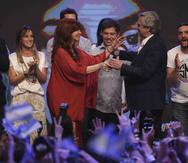 El candidato presidencial peronista Alberto Fernández, al centro enfrente, recibe el micrófono de su compañera de fórmula, la expresidenta Cristina Fernández. (AP)