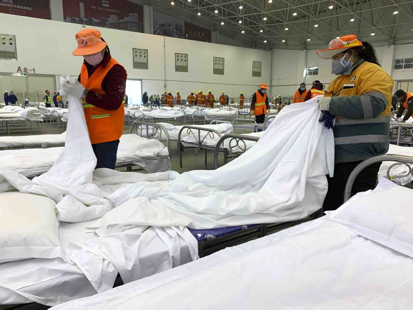 Trabajadores preparando camas en un centro de convenciones convertido en hospital temporal en Wuhan, en la provincia china de Hubei. (AP)