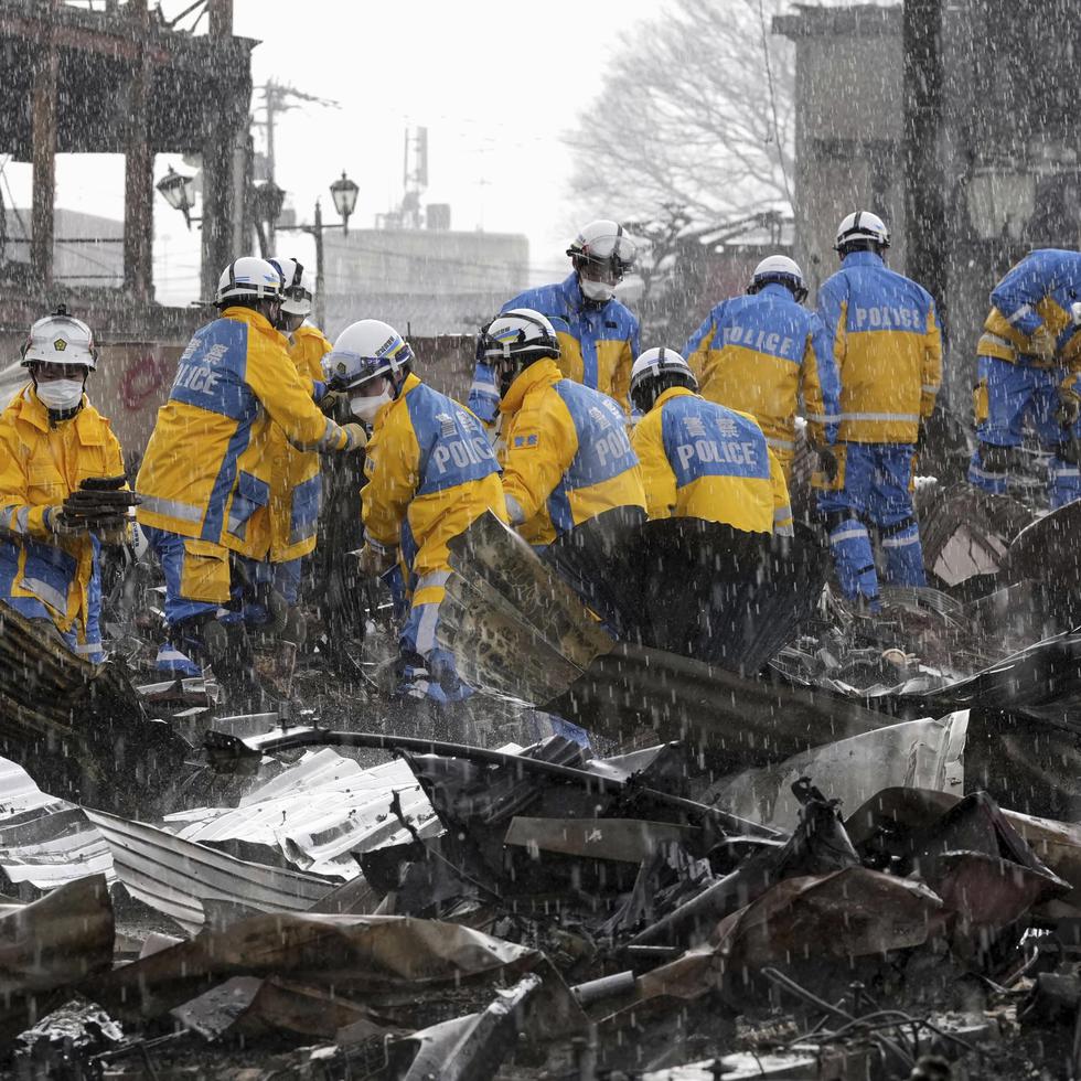 Cae la lluvia mientras agentes de policía retiran escombros tras un incendio en un mercado en Wajima, prefectura de Ishikawa, Japón, el sábado 6 de enero de 2024.
