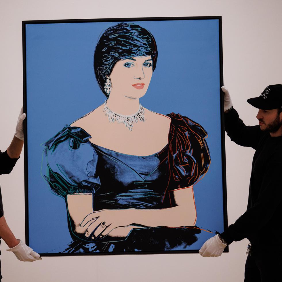 Los asistentes de la galería posan con una pintura titulada 'Retrato de la princesa Diana' del artista estadounidense Andy Warhol durante una vista previa de prensa para las subastas de arte contemporáneo y del siglo XX de la casa de subastas Phillips en Londres, Gran Bretaña.