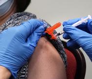 Una mujer recibe una dosis de la vacuna contra COVID-19 por parte de un farmacéutico en una clínica de Lawrence, Massachusetts.