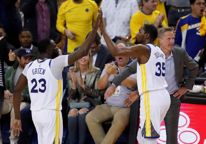 El jugador de los Warriors de Golden State, Draymond Green, choca los cinco con su compañero de equipo Devin Durant, junto a su entrenador Steve Kerr, durante el quinto partido de la serie de primera ronda de la Conferencia Oeste de la NBA. (AP)