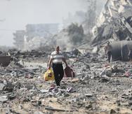 Algunos palestinos caminan junto a edificios destruidos tras un bombardeo israelí sobre Al Zahra, el viernes 20 de octubre de 2023, en las afueras de la Ciudad de Gaza.