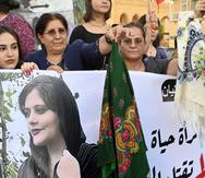 Manifestantes muestran una foto de Mahsa Amini, quien falleció bajo la custodia de la policía moral por, supuestamente, violar la ley de hiyab.