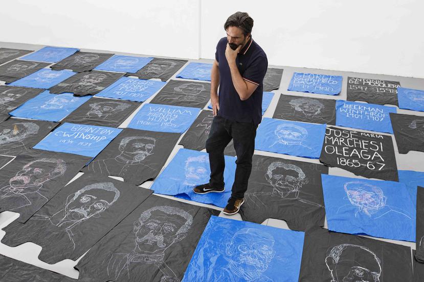 José Lerma camina sobre su obra “Veritedero”, compuesta por cerca de 160 bolsas de basura pintadas con retratos de los gobernadores que en distintos períodos han liderado Puerto Rico. (Raquel Pérez Puig)