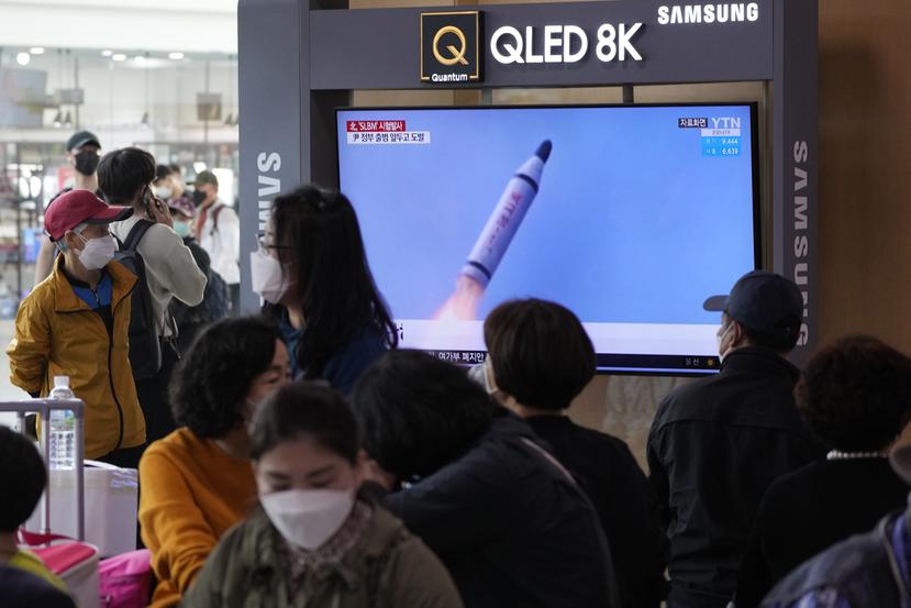 La gente mira un televisor que muestra una imagen de archivo del lanzamiento de un misil de Corea del Norte durante un programa de noticias en la estación de tren en Seúl, Corea del Sur.