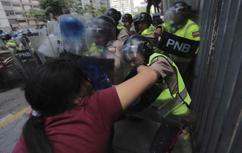 Una mujer se enfrenta a las fuerzas de seguridad venezolanas durante choques entre miembros de la oposición y la policía en Caracas. (AP)