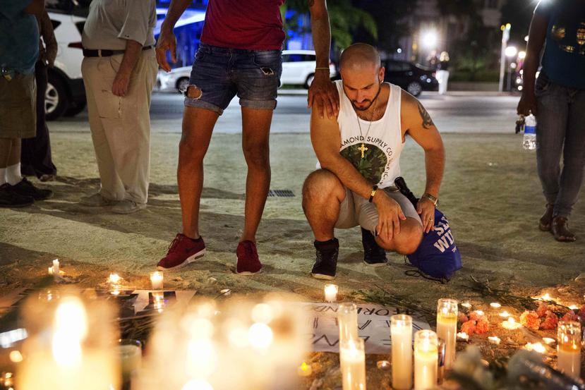 Ronny Torres (d) es consolado por un amigo mientras visitan un memorial en honor a las víctimas de la barra gay Pulse. (AP)