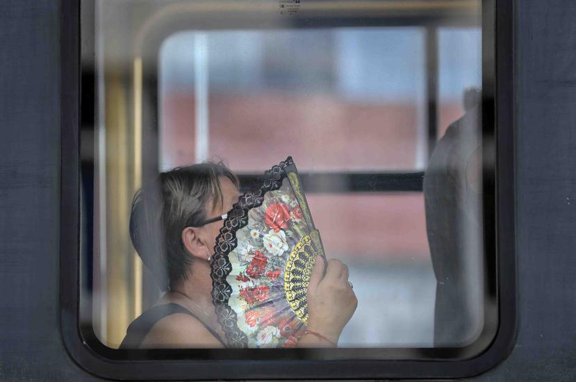 Una mujer usa un abanico para refrescarse mientras viaje en un tram en Bucarest, Rumania. (AP / Vadim Ghirda)