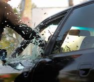 Simulación de un hombre que rompe el cristal de un carro para robar.