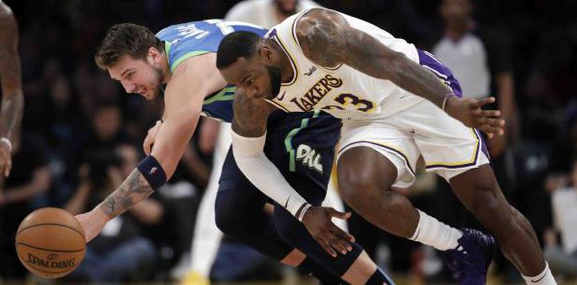 Luka Doncic, a la izquierda, de los Mavericks, y LeBron James, de los Lakers, van ambos tras una bola suelta durante el desafío del domingo. (AP / Marcio José Sánchez)