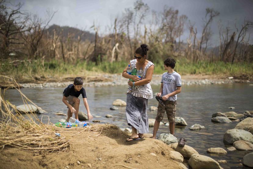 Nancy Gonzalez recoge agua del río junto a sus hijos, Jeremy y Sebastian Harris.