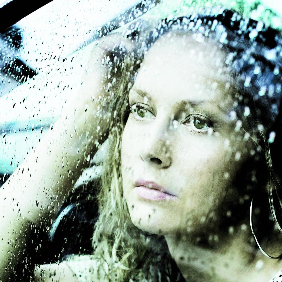 Sad young woman looking through window with a rain drops.
-----
