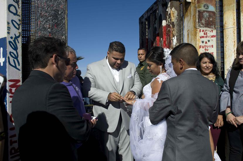 Brian Houston le pone un anillo a su prometida, Evelia Reyes, durante la celebración de su boda en la frontera entre los Estados Unidos y México. (EFE / David Maung)