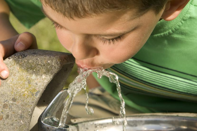 Un niño tomando agua de una fuente