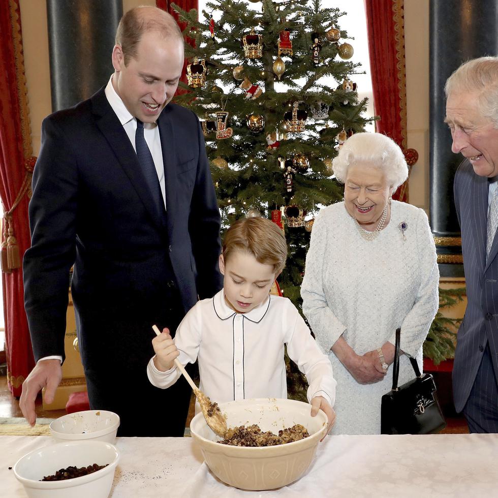 El Palacio de Buckingham difundió una foto especial en que la reina prepara postres navideños con su hijo, su nieto, y su bisnieto. (AP)