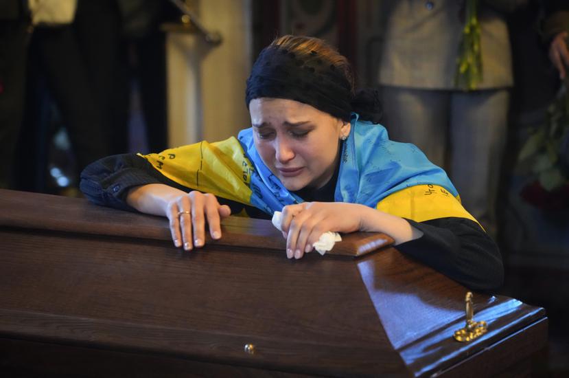 La viuda de un periodista ucraniano asesinado por tropas rusas llora sobre el ataúd.