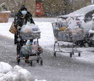Una persona transporta comestibles en un carrito bajo una fuerte nevada en un estacionamiento en Marlborough, Massachusetts, el sábado 5 de diciembre de 2020.