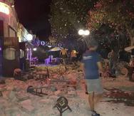 Un hombre yace en el piso mientras otros turistas permanecen afuera de un bar después de un terremoto en la isla griega de Kos. (AP)