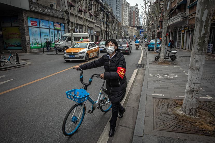 Una voluntaria utiliza una mascarilla mientras camina por las calles de Wuhan, China.