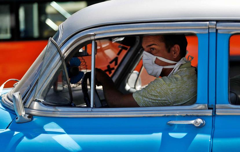 Un taxista cubano es captado con una mascarilla conduciendo ante la emergencia del coronavirus. (AP)